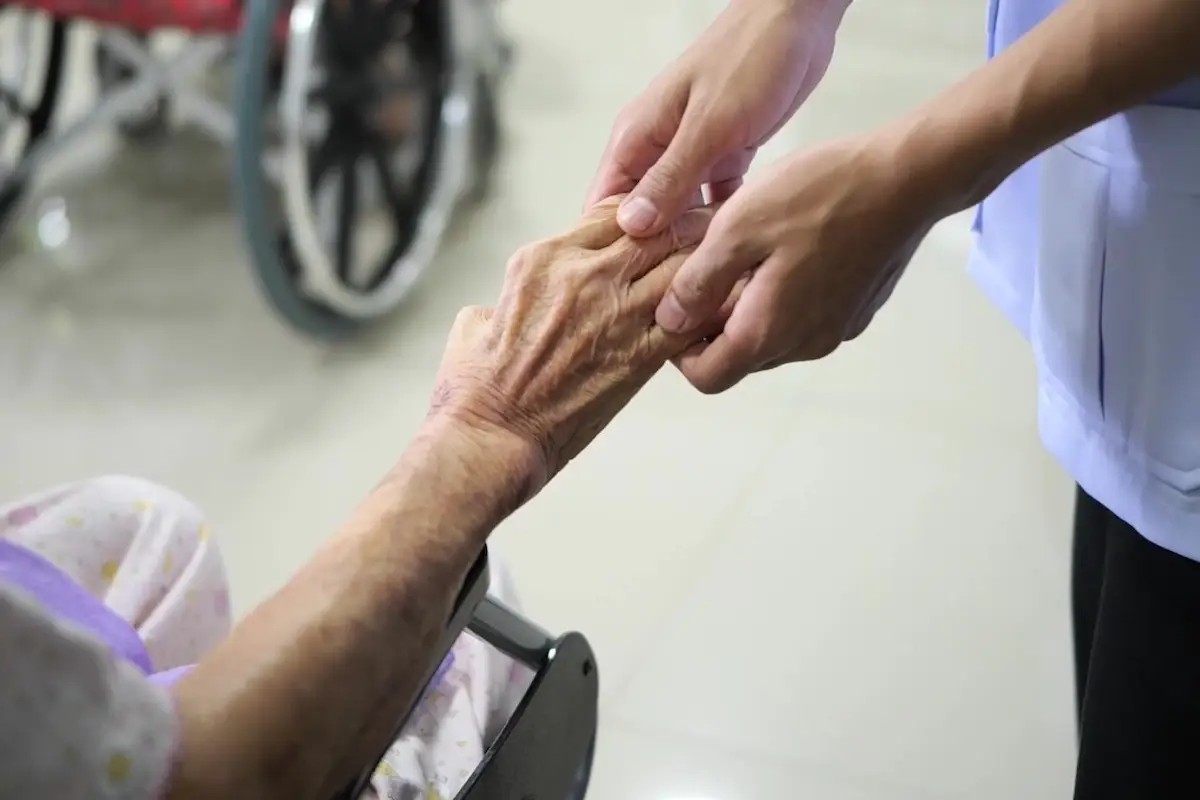 Care staff holding an elderly resident's hand